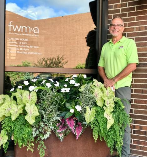 Man standing next to Fort Wayne Museum of Art Sign with plants